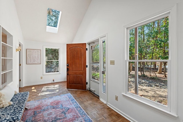 entryway featuring baseboards, lofted ceiling with skylight, and a healthy amount of sunlight