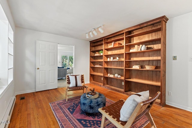 living area with visible vents, track lighting, baseboards, light wood-type flooring, and baseboard heating