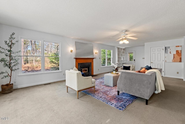 carpeted living room with visible vents, a fireplace with flush hearth, a textured ceiling, and a ceiling fan