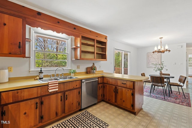 kitchen with light countertops, a peninsula, stainless steel dishwasher, a notable chandelier, and a sink