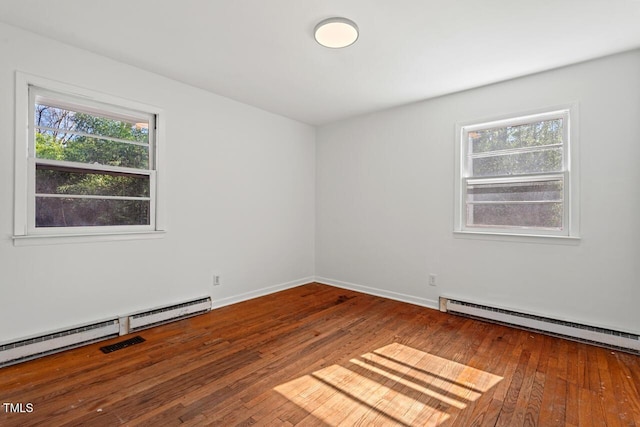 spare room with a baseboard heating unit, wood-type flooring, baseboards, and visible vents