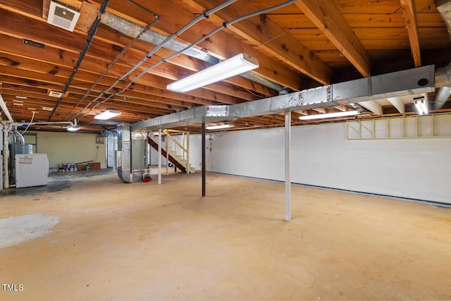 unfinished basement with heating unit and stairs