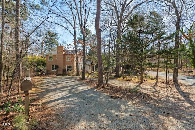 view of front facade featuring a chimney and gravel driveway