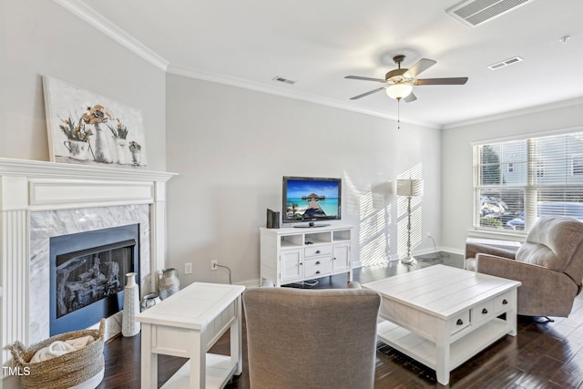 living room featuring ceiling fan, dark wood-type flooring, ornamental molding, and a fireplace