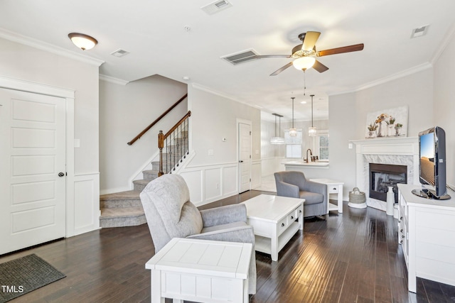 living room featuring dark hardwood / wood-style flooring, a premium fireplace, sink, ceiling fan, and crown molding