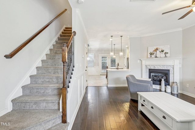 living room featuring ceiling fan, a high end fireplace, crown molding, and dark hardwood / wood-style floors