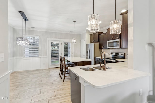 kitchen with kitchen peninsula, appliances with stainless steel finishes, decorative light fixtures, dark brown cabinets, and sink