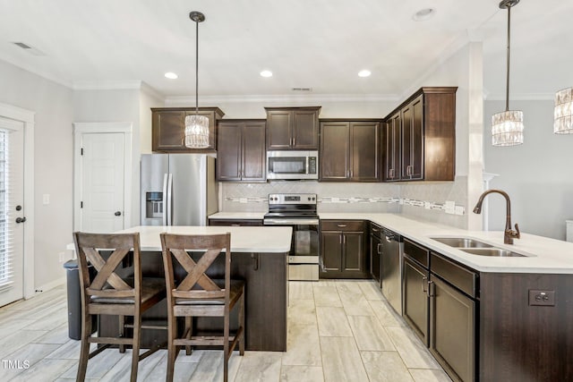 kitchen featuring decorative light fixtures, sink, appliances with stainless steel finishes, and crown molding