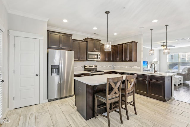 kitchen featuring kitchen peninsula, appliances with stainless steel finishes, hanging light fixtures, dark brown cabinetry, and sink