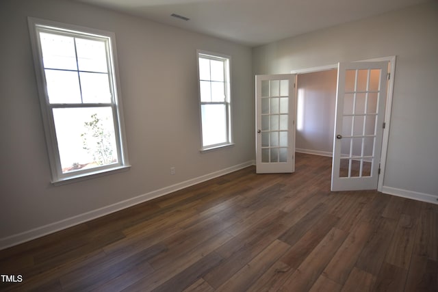 spare room with french doors, plenty of natural light, dark wood finished floors, and visible vents