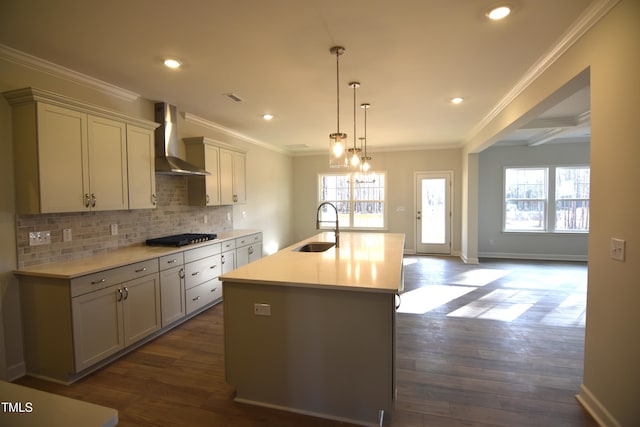 kitchen with tasteful backsplash, wall chimney exhaust hood, dark wood-type flooring, gas cooktop, and a sink