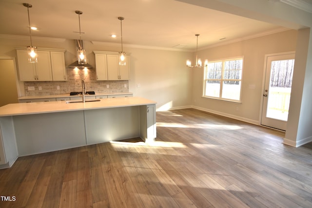 kitchen featuring ornamental molding, light countertops, decorative backsplash, and wood finished floors