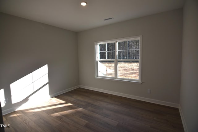 empty room with recessed lighting, visible vents, dark wood finished floors, and baseboards