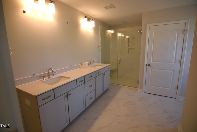 bathroom featuring marble finish floor, a sink, a shower stall, and double vanity