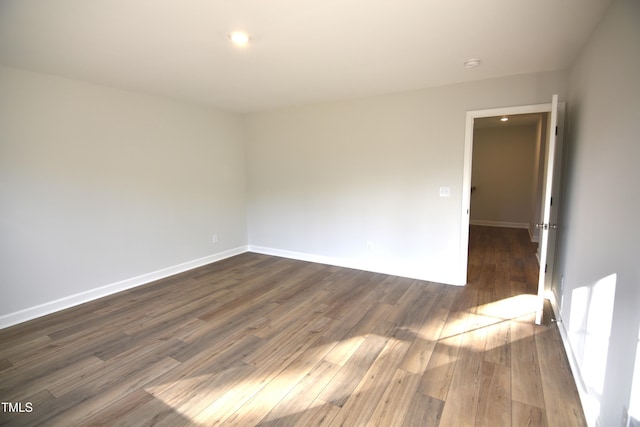 empty room with baseboards and dark wood-type flooring