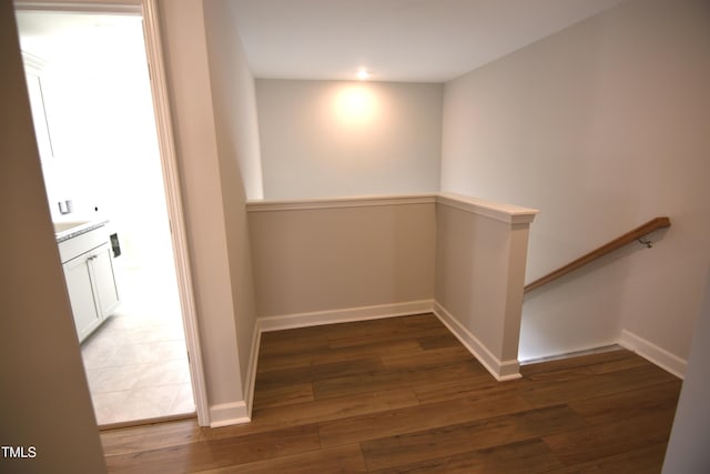 corridor featuring wood-type flooring, baseboards, and an upstairs landing