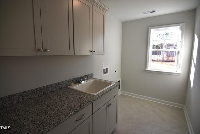 kitchen featuring dark stone countertops, visible vents, a sink, and baseboards