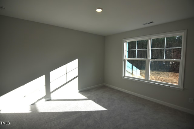 spare room featuring carpet floors, visible vents, and baseboards