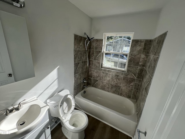 full bathroom with hardwood / wood-style floors, vanity, tiled shower / bath combo, and toilet