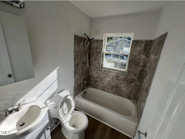 full bathroom featuring hardwood / wood-style floors, tiled shower / bath combo, toilet, and vanity