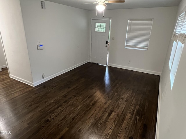 foyer entrance with ceiling fan and dark wood-type flooring