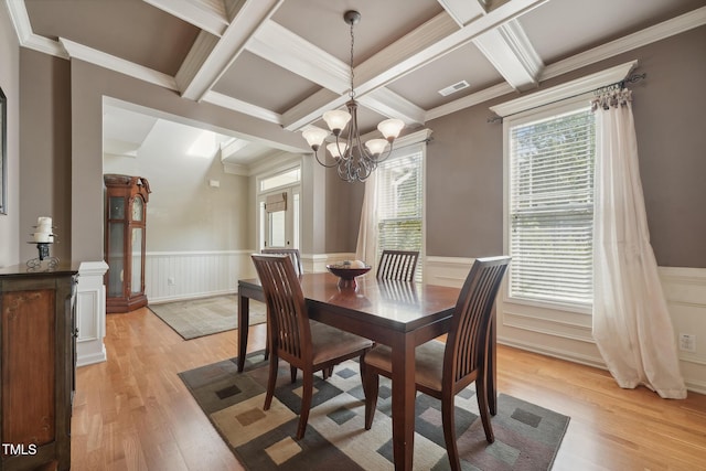 dining space featuring coffered ceiling, ornamental molding, light hardwood / wood-style flooring, and an inviting chandelier