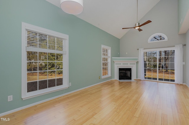 unfurnished living room featuring hardwood / wood-style flooring, a wealth of natural light, high vaulted ceiling, and ceiling fan