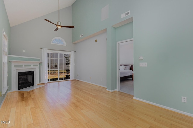 unfurnished living room with a premium fireplace, ceiling fan, light hardwood / wood-style flooring, and high vaulted ceiling