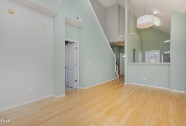 unfurnished living room featuring high vaulted ceiling and light wood-type flooring