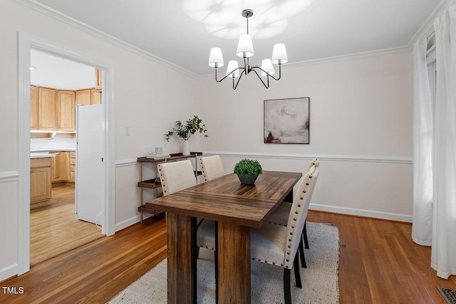 dining room featuring hardwood / wood-style floors, ornamental molding, and a notable chandelier