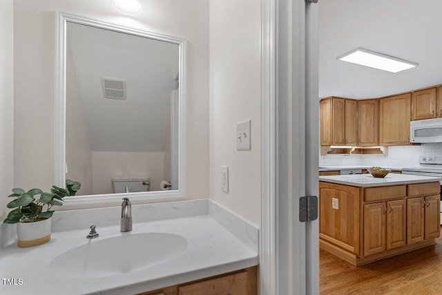 bathroom with sink, toilet, decorative backsplash, and wood-type flooring