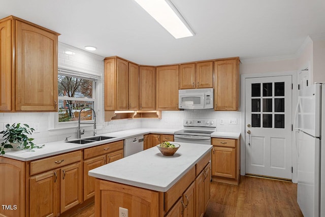 kitchen featuring white appliances, sink, backsplash, and a center island