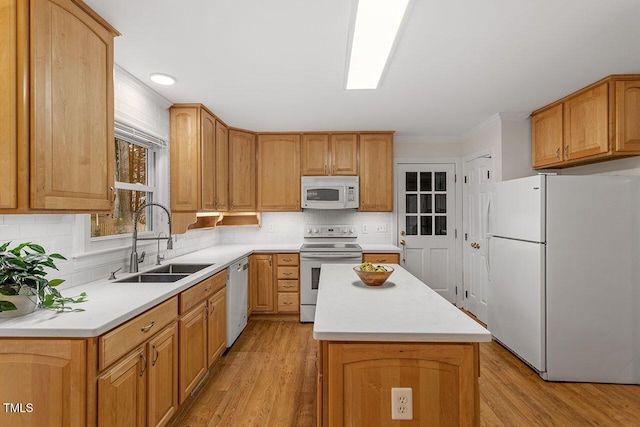 kitchen with white appliances, light wood-type flooring, a center island, sink, and backsplash