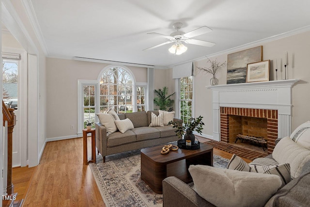 living room with a brick fireplace, a healthy amount of sunlight, and light hardwood / wood-style flooring