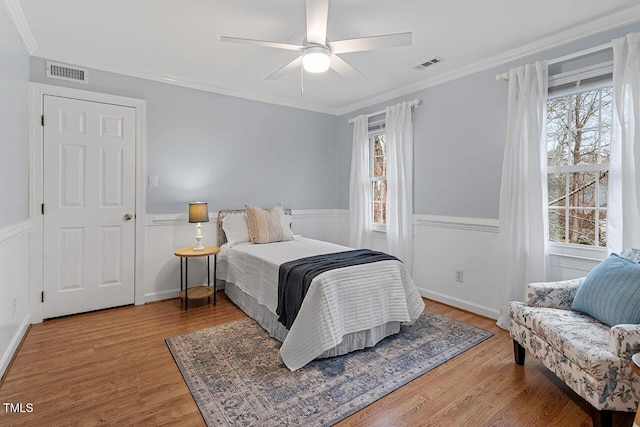 bedroom with multiple windows, ceiling fan, hardwood / wood-style flooring, and crown molding