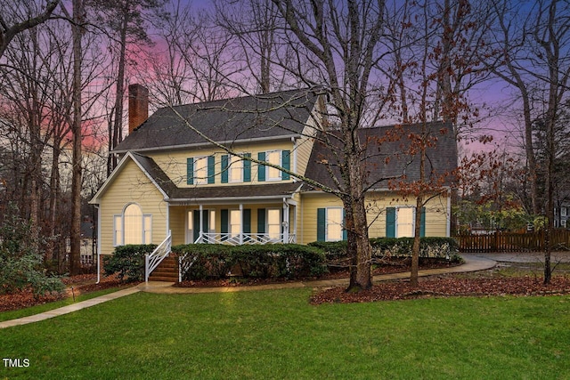 view of front of property featuring covered porch and a yard