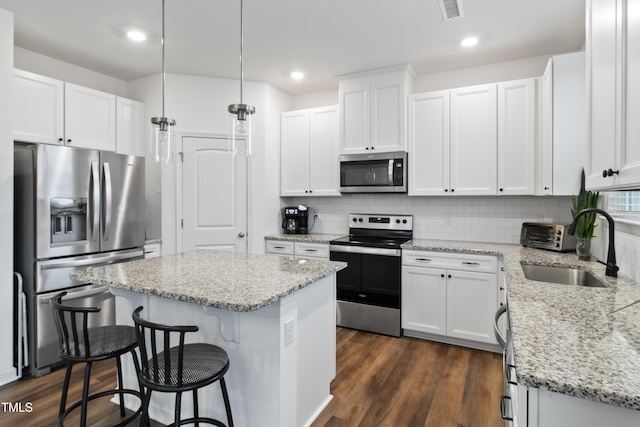 kitchen featuring white cabinets, pendant lighting, a center island, and stainless steel appliances