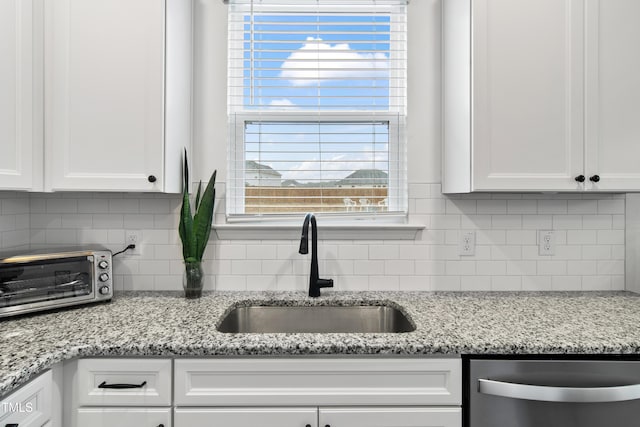 kitchen featuring light stone countertops, sink, white cabinets, and stainless steel dishwasher