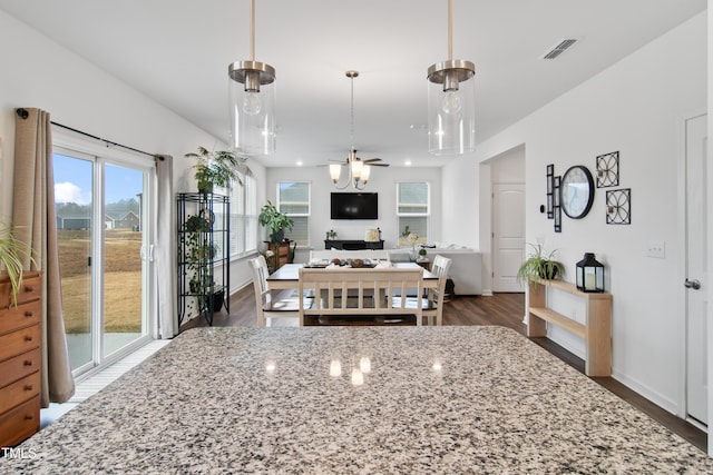 kitchen with decorative light fixtures, ceiling fan, light stone counters, and dark hardwood / wood-style floors