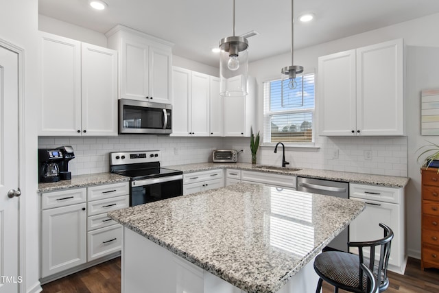 kitchen with decorative light fixtures, a center island, white cabinetry, and stainless steel appliances