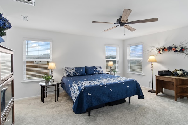 bedroom with multiple windows, ceiling fan, and light carpet