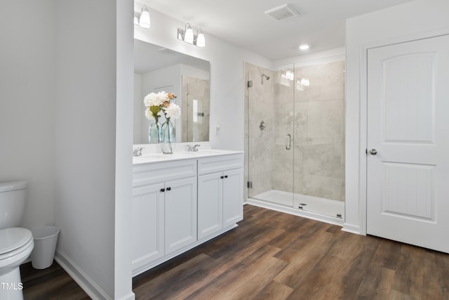 bathroom featuring hardwood / wood-style flooring, vanity, toilet, and a shower with door