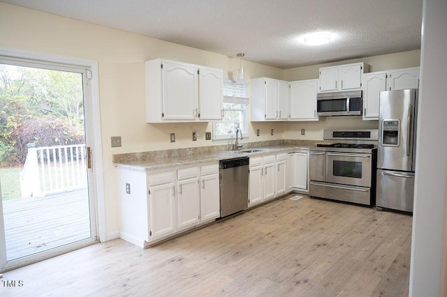 kitchen featuring a textured ceiling, stainless steel appliances, white cabinetry, and plenty of natural light