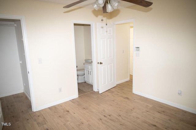 unfurnished bedroom featuring connected bathroom, ceiling fan, light hardwood / wood-style floors, a walk in closet, and a closet