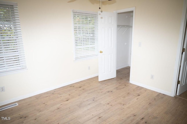 unfurnished bedroom with a closet, light hardwood / wood-style flooring, and a spacious closet