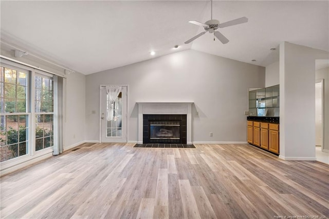 unfurnished living room featuring ceiling fan, a fireplace, lofted ceiling, and light wood-type flooring