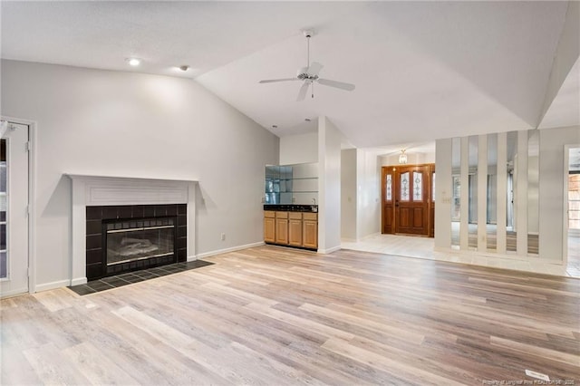 unfurnished living room with a tile fireplace, ceiling fan, light hardwood / wood-style floors, and lofted ceiling