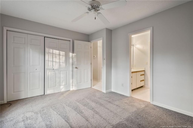 unfurnished bedroom with connected bathroom, ceiling fan, a closet, and light colored carpet