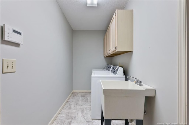 washroom featuring a textured ceiling, washer and dryer, cabinets, and sink