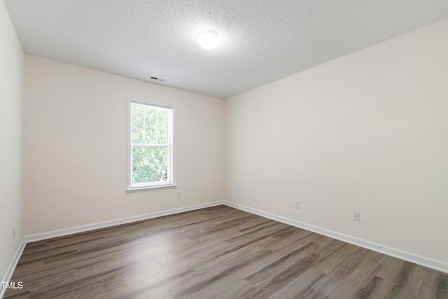 spare room featuring wood finished floors, baseboards, and a textured ceiling